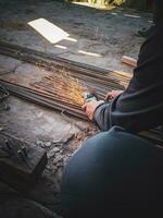 a man is cutting iron ingots with a hand grinder photo