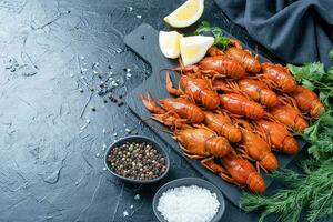 cooked crawfish on platter with lemons and spices on dark background photo