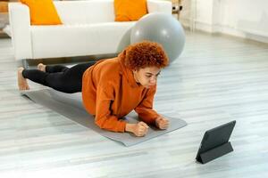 Fitness Workout training. Young healthy fit african girl doing plank exercise on yoga mat on floor at home. Athletic woman in sportswear training pilates. Sport and fitness. photo