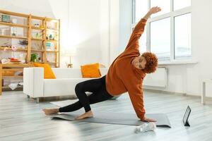 Fitness Workout training. Young healthy african girl practicing yoga at home. Woman in sportswear training pilates doing sports exercise on yoga mat on floor indoor. Girl have training workout. photo