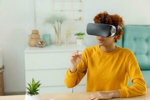 African american young woman wearing using virtual reality metaverse VR glasses headset at home. Girl touching air during VR experience on virtual reality helmet. Simulation hi-tech videogame concept. photo