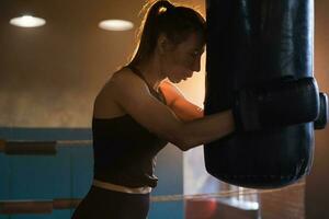 mujer yo defensa niña fuerza. fuerte mujer combatiente descansando después lucha formación en boxeo anillo. fuerte niña cansado después puñetazos boxeo bolsa. formación día en gimnasia. fuerza ajuste cuerpo rutina de ejercicio capacitación. foto