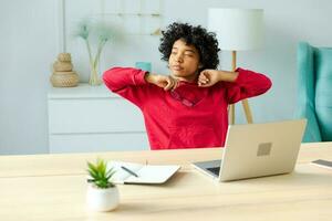 African american girl at home office relaxing stretching hands and body taking break from work on laptop. Joyful young woman freelancer businesswoman happy after work done satisfied by good result. photo