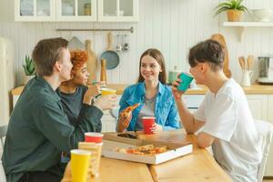 Home party Friends spending time together having fun laughing communicating at home. Happy diverse group eating pizza drinking beer or lemonade. Mixed race young buddies best friends enjoying weekend. photo