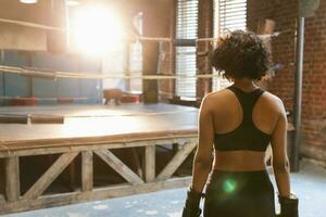 mujer yo defensa. africano mujer combatiente preparando para competencia lucha yendo a boxeo anillo. fuerte niña Listo para lucha activo ejercicio combate rutina de ejercicio capacitación. formación día en boxeo gimnasia. foto