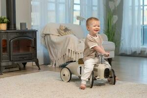 Happy child at home. Little toddler boy driving big vintage toy car and having fun. Smiling kid playing at home. Baby boy playing with toy in living room indoors. photo