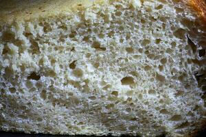 un rebanada de centeno un pan con un crujiente corteza y textura en el agujero. Fresco hecho en casa de masa fermentada un pan. foto en alto calidad