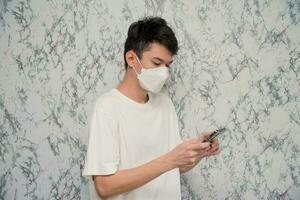 Man puts on a face mask using smartphone isolated on White background,pandemic and social distancing concept.Covid-19 photo