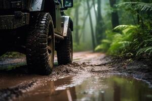 Four wheel drive SUV is driving on muddy road in jungle. photo