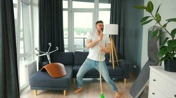 uomo pulizia il Casa e avendo divertimento danza con un' scopa. lento movimento video