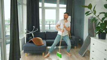 hombre limpieza el casa y teniendo divertido bailando con un escoba. lento movimiento video