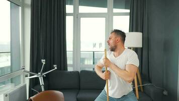 Man cleaning the house and having fun dancing with a broom. Slow motion video