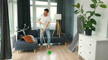 Man cleaning the house and having fun dancing with a broom. Slow motion video