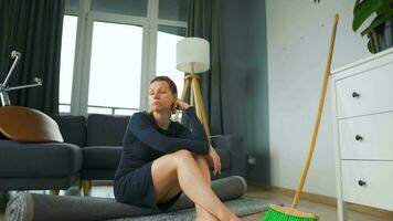 Woman sits in the middle of the room deep in thought. She needs to clean up, but she procrastinates video