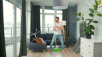 Man cleaning the house and having fun dancing with a broom. Slow motion video