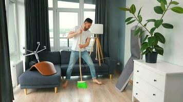 hombre limpieza el casa y teniendo divertido bailando con un escoba. lento movimiento video