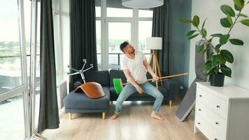 Man cleaning the house and having fun dancing with a broom. Slow motion video