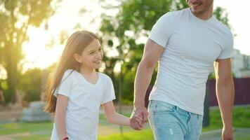 papà e figlia camminare in giro loro la zona a tramonto. bambino detiene Il padre di mano video