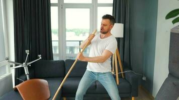 hombre limpieza el casa y teniendo divertido bailando con un escoba. lento movimiento video