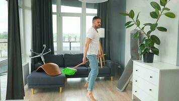 Man cleaning the house and having fun dancing with a broom. Slow motion video