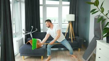 Man cleaning the house and having fun dancing with a broom. Slow motion video