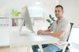 Young man using computer while sitting in chair. photo