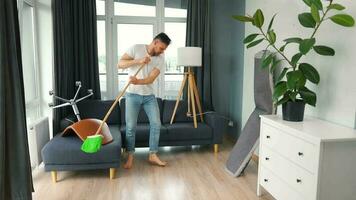 homem limpeza a casa e tendo Diversão dançando com uma vassoura. lento movimento video