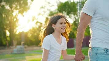 papà e figlia camminare in giro loro la zona a tramonto. bambino detiene Il padre di mano video