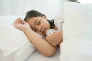 el niña duerme en un cómodo blanco dormitorio. foto