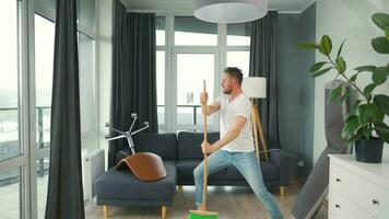 hombre limpieza el casa y teniendo divertido bailando con un escoba. lento movimiento video