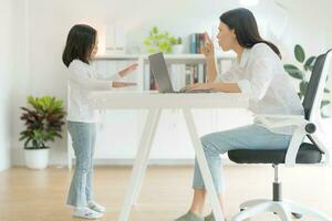 Mother trying to work at home office and daughter. photo