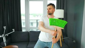 hombre limpieza el casa y teniendo divertido bailando con un escoba. lento movimiento video
