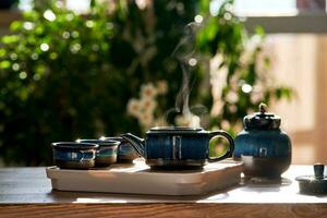 Tea set of deep blue color on a background of greenery. photo