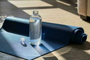 Reusable glass water bottle on yoga mat. photo