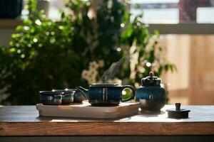 Tea set of deep blue color on a background of greenery. photo