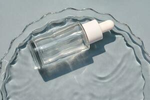 A bottle of serum in water on a blue background. photo