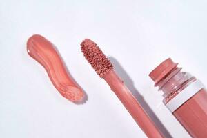 Red lip gloss with applicator and smear. photo