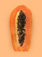 Half of ripe papaya fruit with seeds on a color background. Appetizing tropical fruit photo