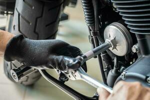 mechanic use oil filter wrench removal tool on motorcycle at garage ,concept of motorcycle maintenance and repair. selective focus photo