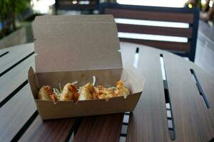 Fried gyozas in brown paper box on wood table. photo