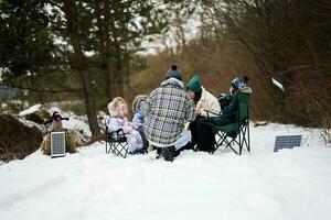 familia con Tres niños en invierno bosque gasto hora juntos en un picnic. foto