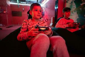 Two boys gamers play gamepad video game console in red gaming room. photo