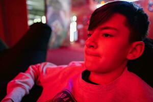 adolescente chico jugador jugar gamepad vídeo juego consola en rojo juego de azar habitación. foto