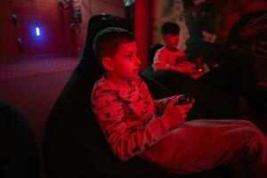 Two boys gamers play gamepad video game console in red gaming room. photo