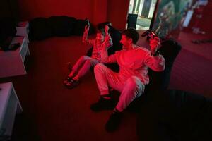 Father and son play gamepad video game console in red gaming room. Dad and kid gamers. photo