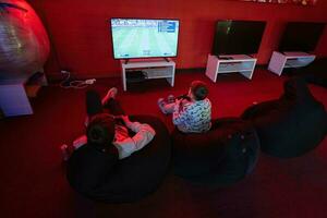 Two boys gamers play gamepad video game console in red gaming room. photo