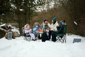 Family with three children in winter forest spending time together on a picnic. photo