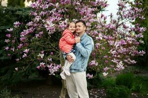 Happy Father's Day. Father with daughter in hands enjoying nice spring day near magnolia blooming tree. photo