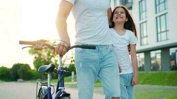 Dad is teaching daughter how to ride bicycle at sunset. Slow motion video