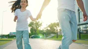 papá y hija caminar alrededor su zona a puesta de sol. niño sostiene del padre mano video